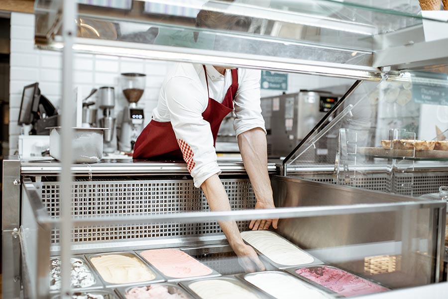 Verkäufer füllt eine Kühltruhe mit neuer Ware auf